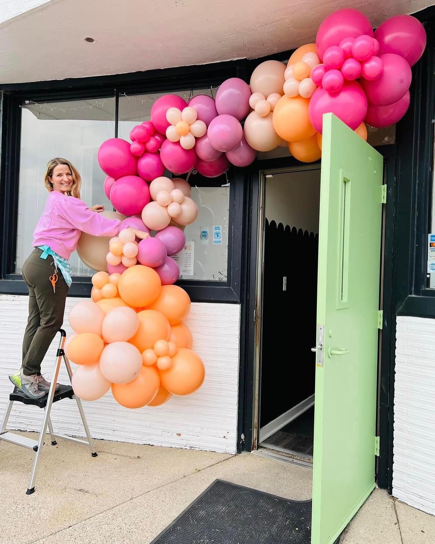 woman standing outside setting up an organic balloon garland