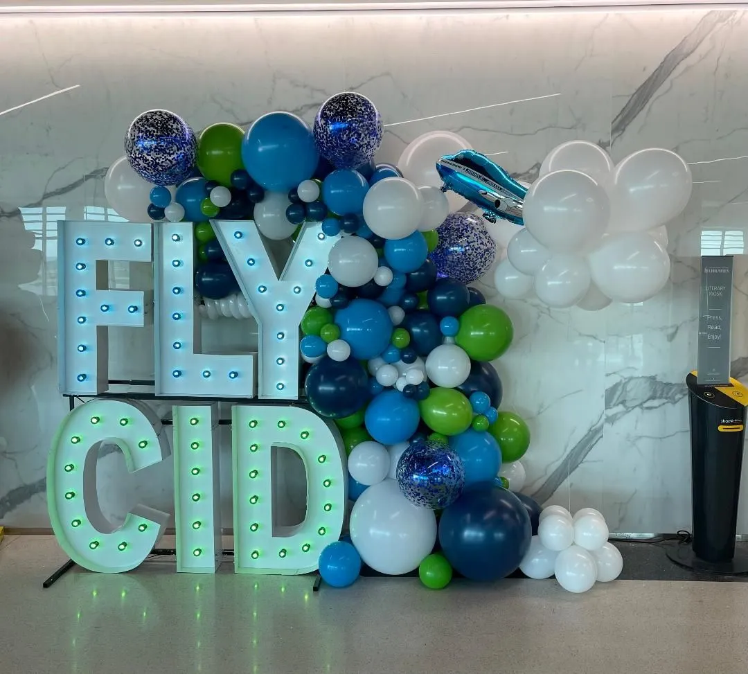 light up marquee spelling FLY CID with multi colored balloon garland