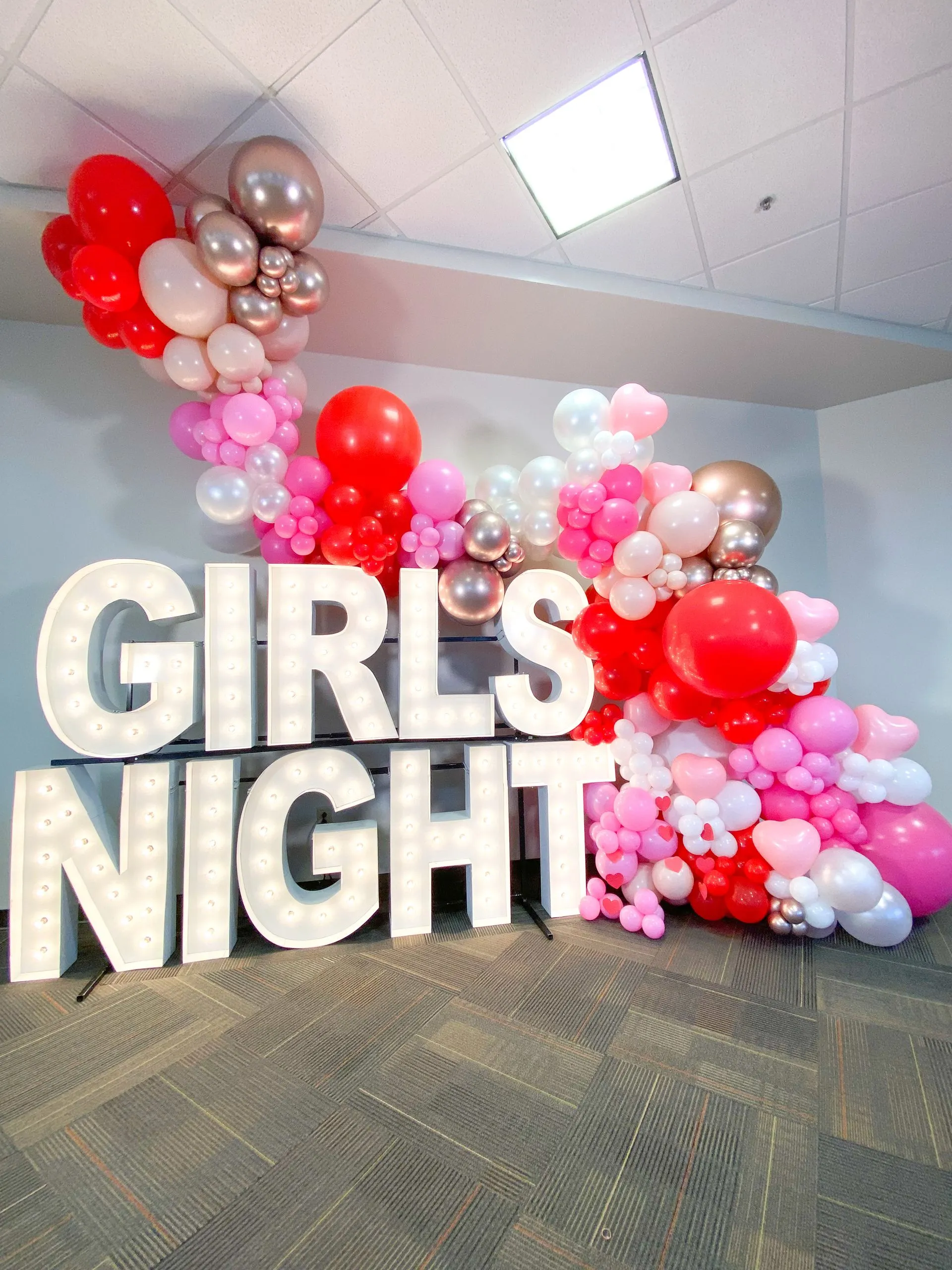 light up marquee spelling GIRLS NIGHT with organic balloon garland