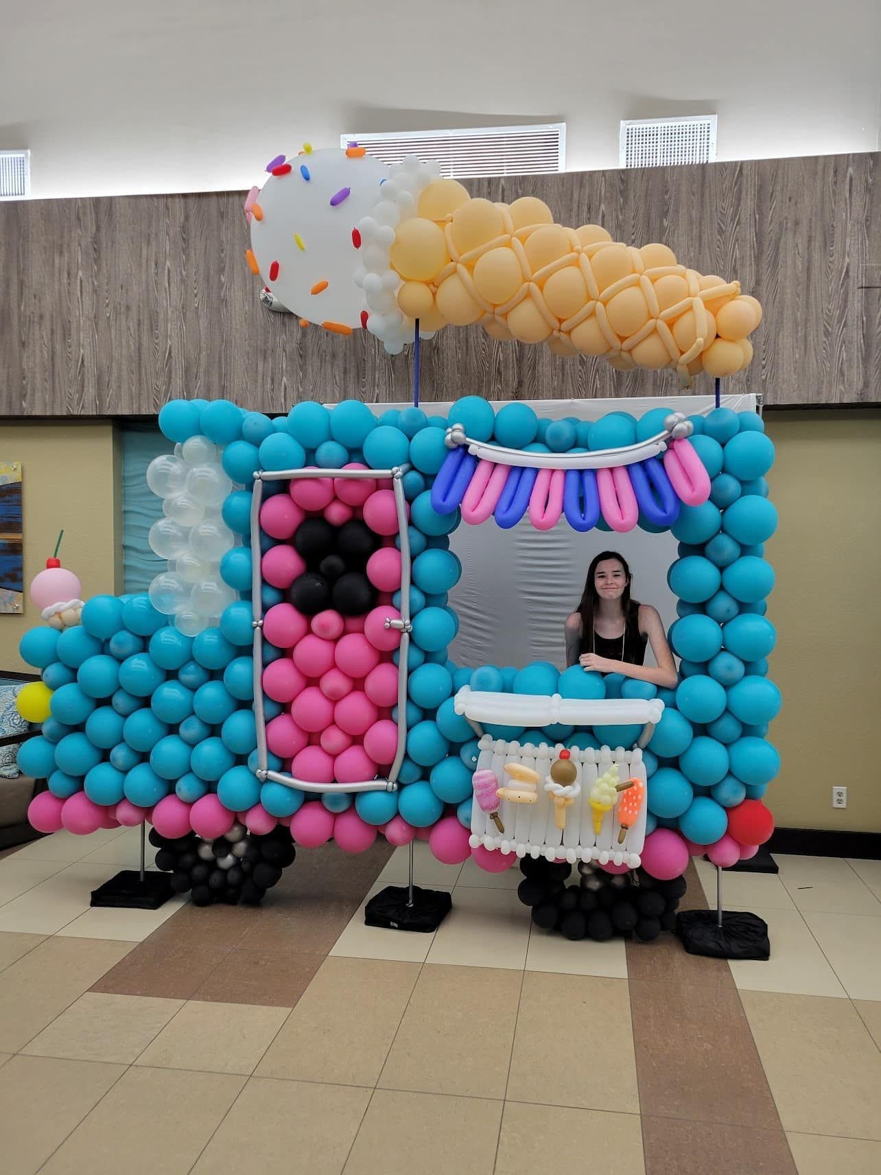 ice cream truck balloon decor sculpture with ice cream cone on top and girl in window