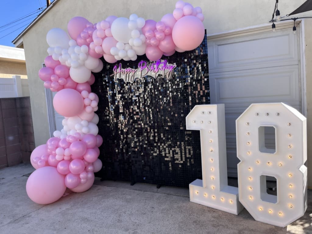 18th birthday balloon decor installation with light up marquees and a pink balloon garland