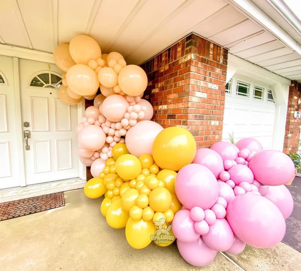 organic balloon garland outside that is pink, gold, and beige