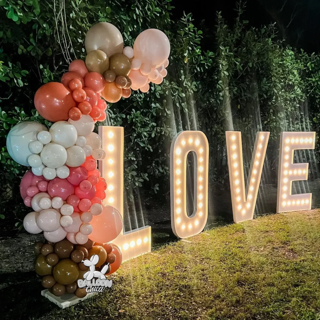 light up marquee spelling LOVE with an organic balloon garland