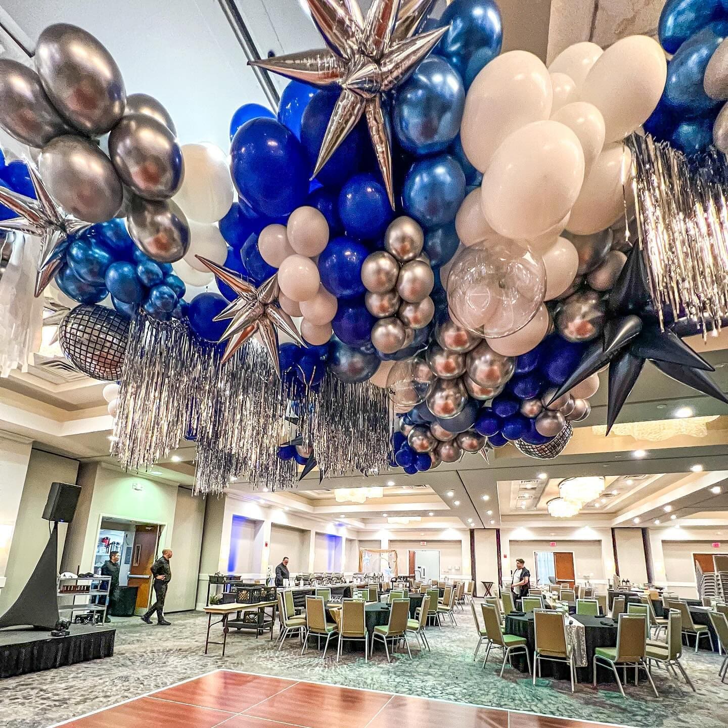 blue, white, and silver balloon ceiling inside at at corporate event