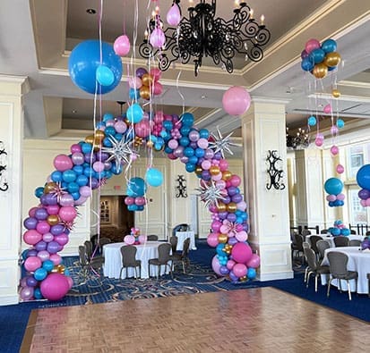 a dance hall decorated with an assortment of balloon decorations including a balloon arch and balloon centerpieces