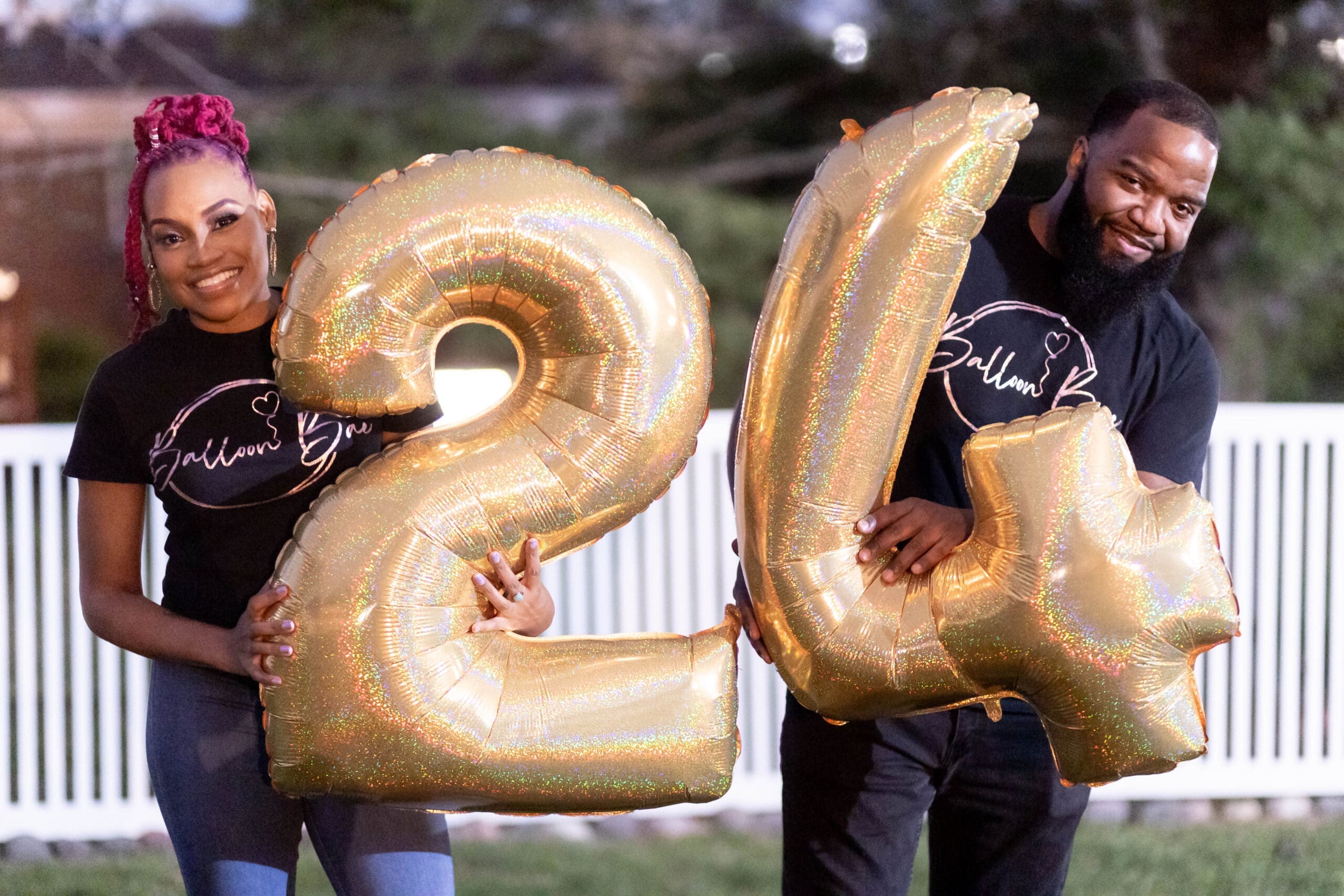 two people holding large foil balloon numbers 2 and 4