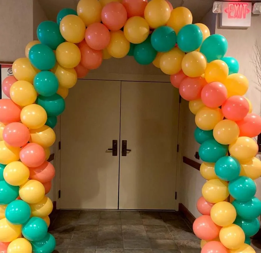 yellow, green, and salmon balloon arch above door