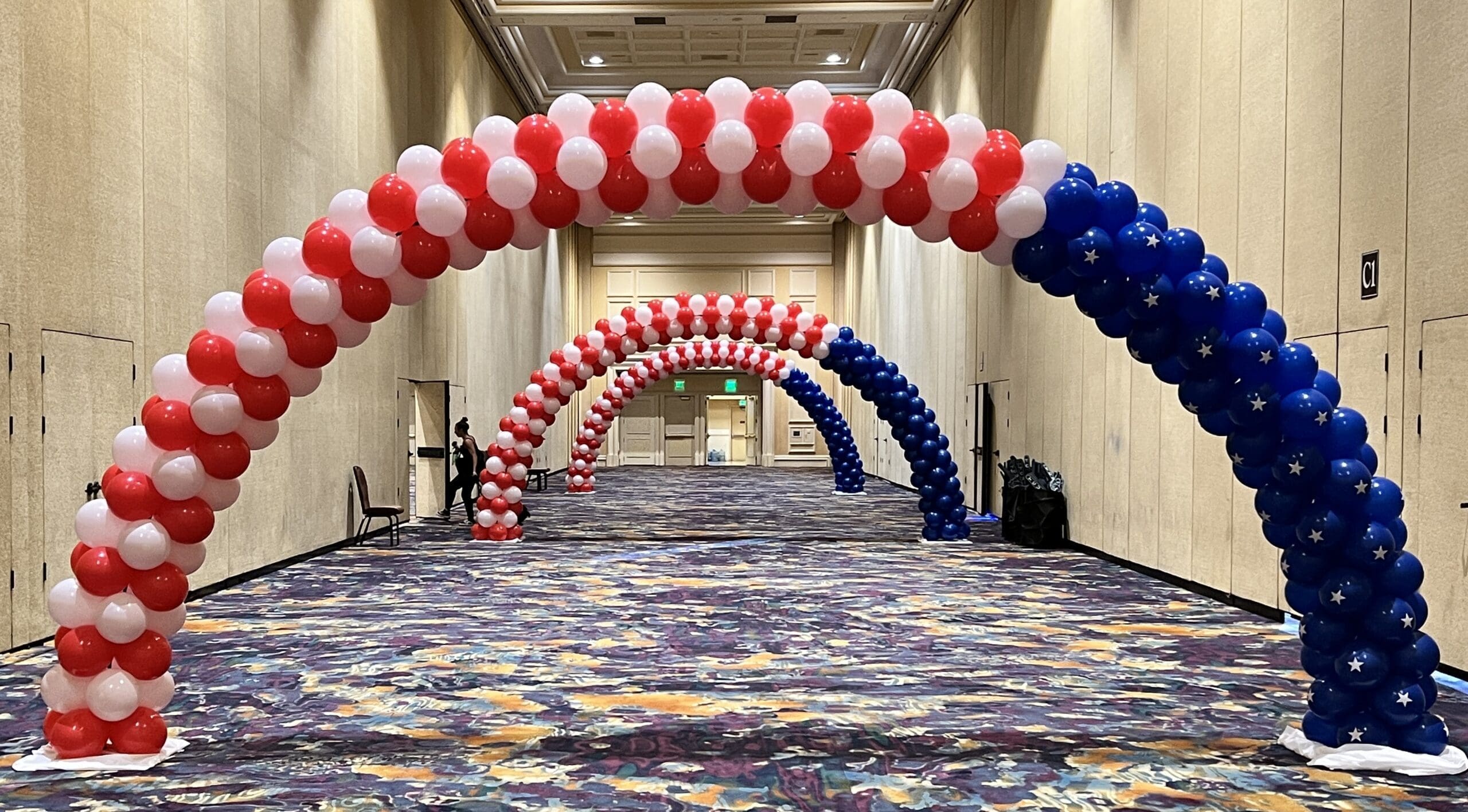 red, white, and blue balloon arches in a hallway