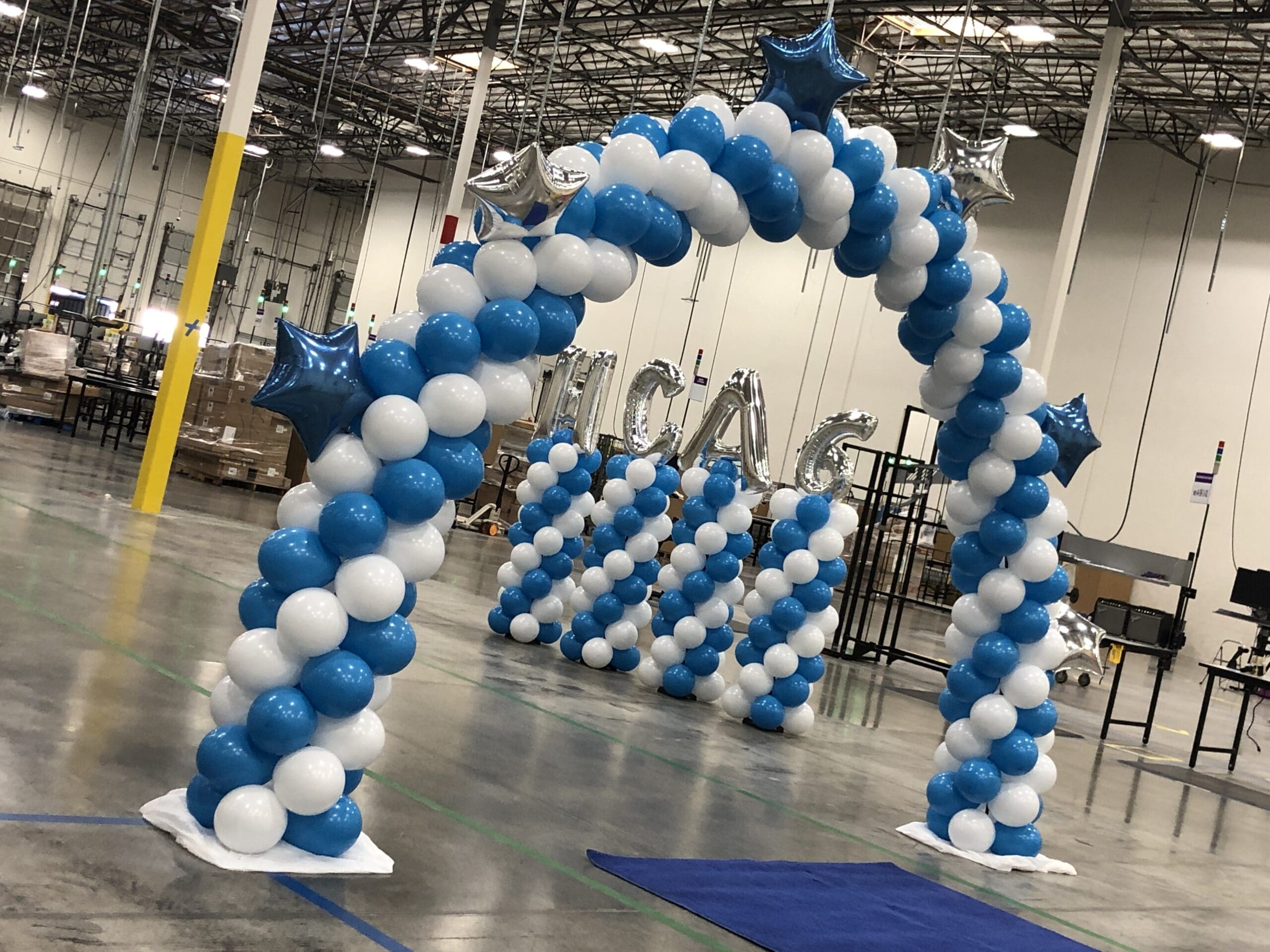 A blue and white balloon arch with 4 balloon columns in the background