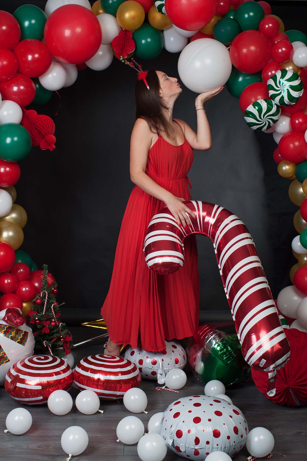 Woman in red dress near balloon arch